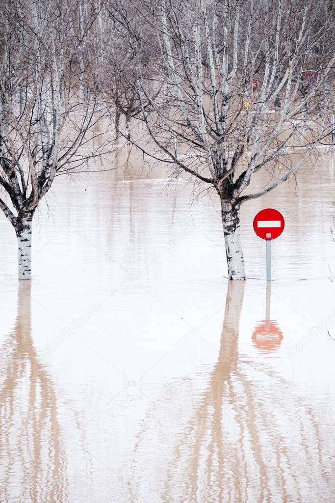 A stop traffic sign and trees underwater after a strong flooding in Zaragoza, Spain. Closed roads due to storm effects