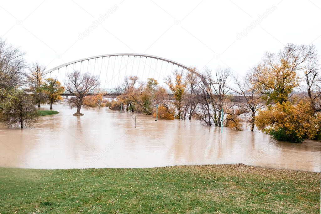 Riverside of Zaragoza is covered by water due to strong flood after strom Barra. Street lights and trees are underwater. Tercer Milenio bridge in the background