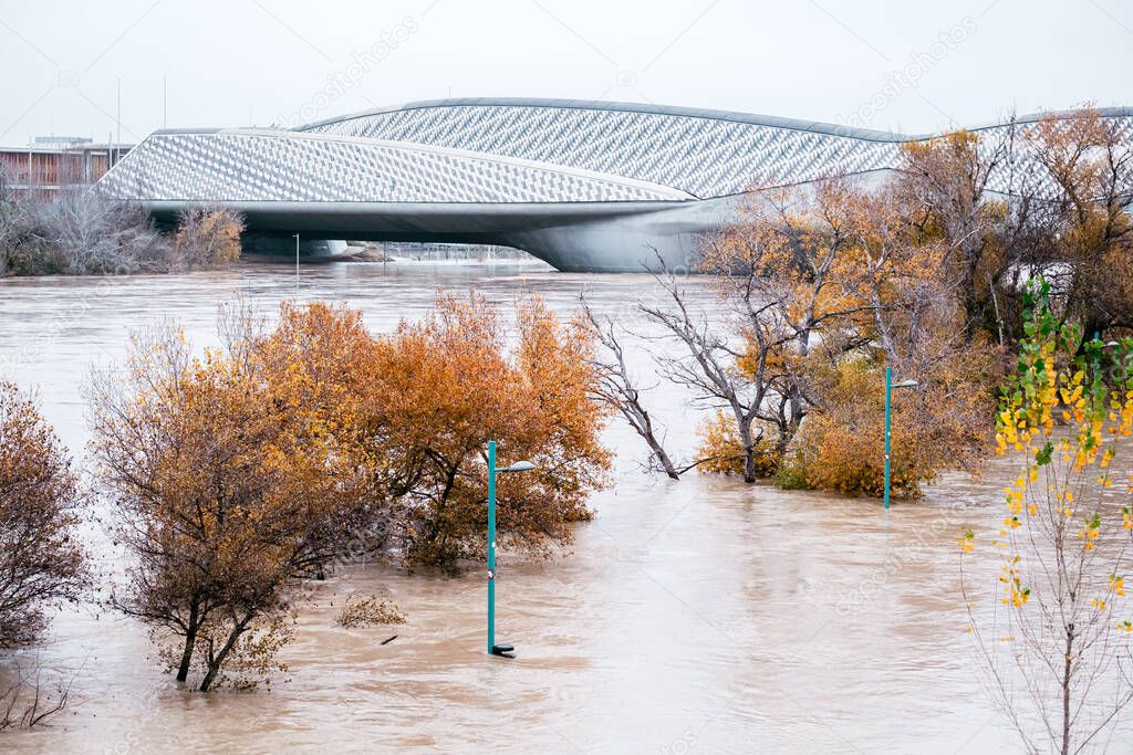 Riverside of Zaragoza is covered by water due to strong flood after strom Barra. Street lights and trees are underwater. Pabelln puente in the background 