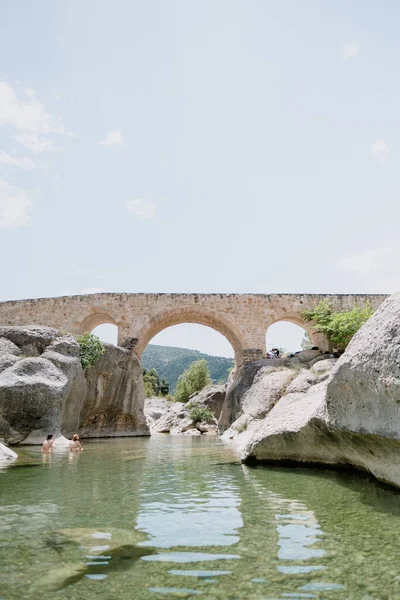A hidden gem natural pool in Teruel, a region of Spain. This spot is perfect for summer and heatwaves due to high temperatures. Tourists from urban areas come to swim. Roman bridge at the background