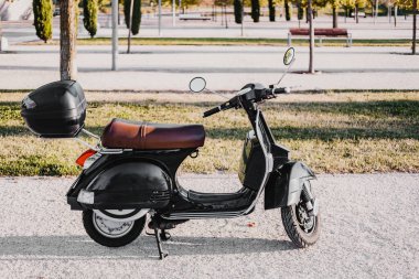 Horizontal picture of black vintage retro motorbike. There is a square black and white pattern at the front. It second hand and has brown leather seat and a basket at the back.