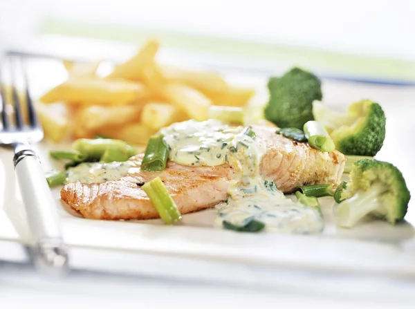 Baked salmon served on a plate with vegetables and fries — Stock Photo, Image
