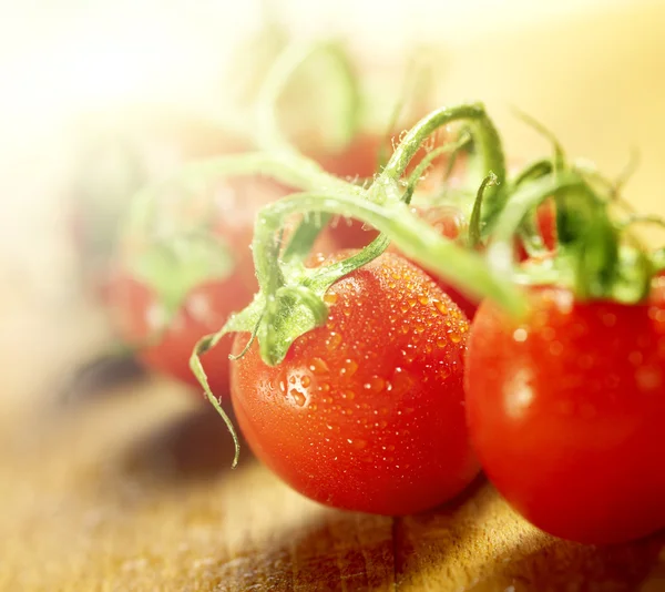 Los tomates sobre la vid sobre la tabla de cortar de madera —  Fotos de Stock