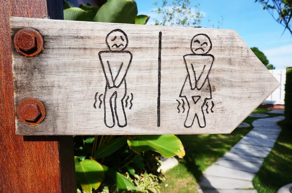 A wooden sign hung over the entrance to a toilet — Stock Photo, Image