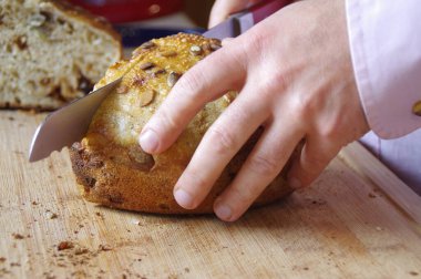 Adam taze ev yapımı ekmek kesiyor. Sağlıklı organik bir fırınla sabah kahvaltısı. Bir dilim tahıllı kek ve elinde bir bıçak..