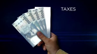 Chile Peso paper note holding. Fan of CLP banknotes in hand. Metaphor concept of income loss, cost of live, tax, credits and money decline.