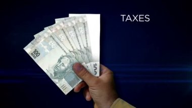 Brezilya Emlak, Reai kağıt notu tutuyor. BRL banknotlarının hayranı. Gelir kaybı, yaşam, vergi, kredi ve para kaybı metaforu.