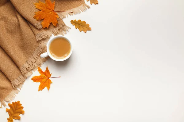 Bej kaşmir eşarp, sonbahar akçaağaç yapraklı bir fincan kahve ve gri arka planda meşe yaprakları. Düz konum, üst görünüm, kopyalama alanı