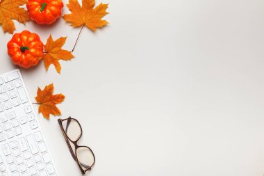 Klavyeli, gözlüklü, balkabaklı sonbahar yapraklı beyaz bir masaüstü manzarası. Düz metin kopyalama alanı