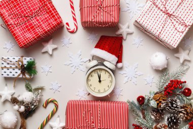 Yeni yıl kış kompozisyonu. Alarm saati Noel Baba şapkalı kutular ve beyaz arka planda köknar dalları. Çerçeve kenarlık düz üst görünüm