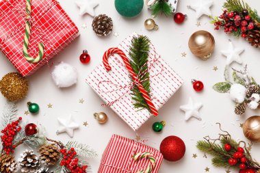 Yeni yıl kış konsepti. Noel kutuları, beyaz arka planda köknar dallarıyla dolu hediyeler. Düz üst görünüm