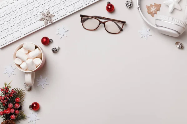 Kış masaüstü. Yeni yıl Noel kompozisyonu. Klavye gözlükleri gri masada marshmallow kulaklıkları hediye eder. Düz üst görünüm