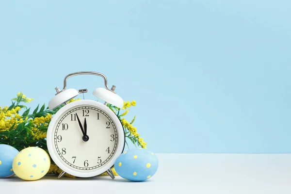イースターのコンセプト 青い背景に目覚まし時計の卵の開花枝 コピースペース — ストック写真