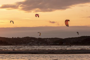 Göteborg, İsveç - 10 Ekim 2021: Kiteboardcular gün batımında plajda uçurtma sörfü yapıyorlar .