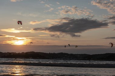 Göteborg, İsveç - 10 Ekim 2021: Kiteboardcular gün batımında plajda uçurtma sörfü yapıyorlar .