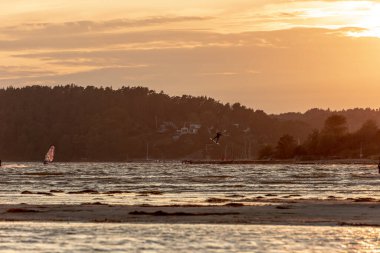 Göteborg, İsveç - 10 Ekim 2021: Kiteboardcular gün batımında plajda uçurtma sörfü yapıyorlar .