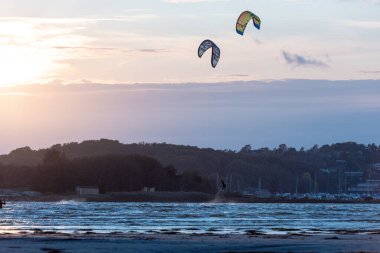 Göteborg, İsveç - 10 Ekim 2021: Kiteboardcular gün batımında plajda uçurtma sörfü yapıyorlar .