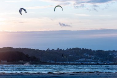 Göteborg, İsveç - 10 Ekim 2021: Kiteboardcular gün batımında plajda uçurtma sörfü yapıyorlar .
