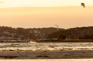 Göteborg, İsveç - 10 Ekim 2021: Kiteboardcular gün batımında plajda uçurtma sörfü yapıyorlar .