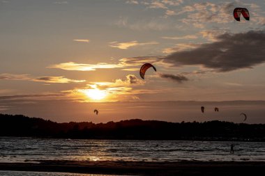 Göteborg, İsveç - 10 Ekim 2021: Kiteboardcular gün batımında plajda uçurtma sörfü yapıyorlar .