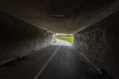 Tünelin sonunda virajı olan koyu renkli bir bisiklet altgeçidi..