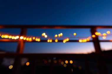 Odak dışı noel ışıkları gece bir balkonun korkuluklarında.