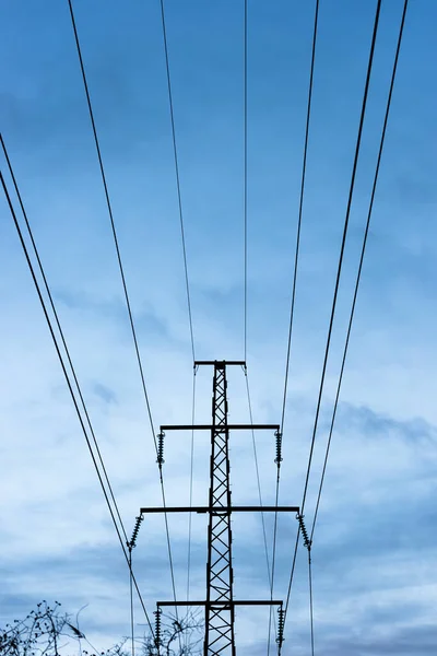 High voltage power lines against a blue cloudy sky.