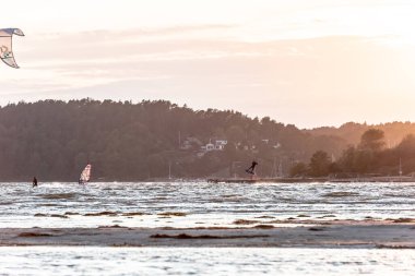 Kiteboardcular gün batımında sahilde uçuyor. .