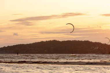 Kiteboardcular gün batımında sahilde uçuyor. .