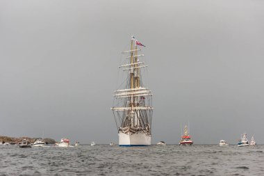 Lindesnes, Norveç - 07 Ağustos 2021: Yelkenli eğitim gemisi Statsraad Lehmkuhl küçük teknelerden oluşan bir donanma tarafından karşılandı.