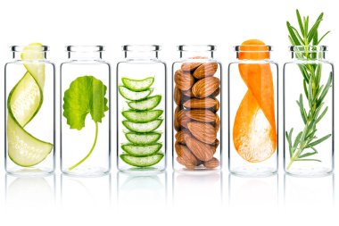 Doğal malzemeli ev yapımı deri bakımı aloe vera, salatalık, badem, sentella asiatika ve biberiye beyaz arka planda izole edilmiş cam şişelerde..
