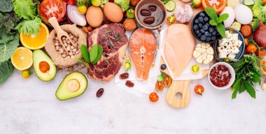 Ketojenik düşük karbonhidrat diyet konsepti. Beyaz beton arkaplan üzerine kurulmuş sağlıklı yiyecekler seçimi için gerekenler.