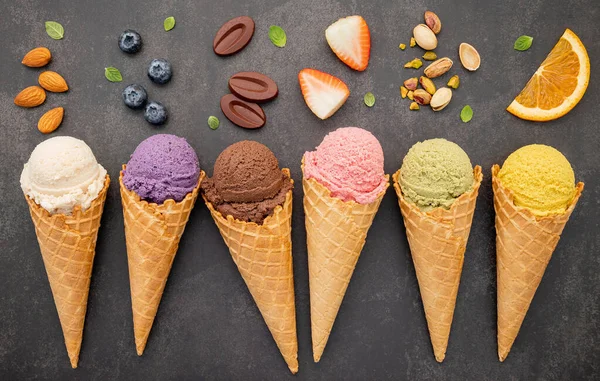 Various of ice cream flavor in cones blueberry ,pistachio ,almond ,orange and chocolate setup on dark stone background . Summer and Sweet menu concept.