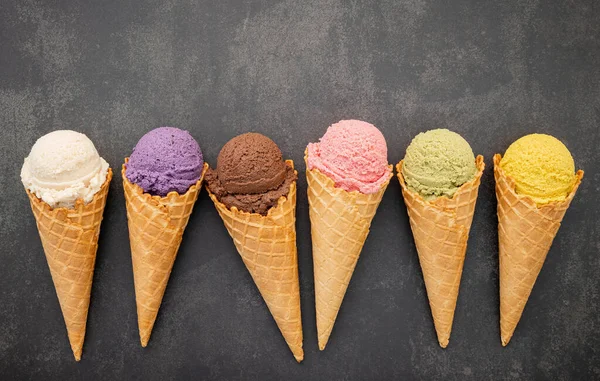 Various of ice cream flavor in cones blueberry ,pistachio ,almond ,orange and chocolate setup on dark stone background . Summer and Sweet menu concept.