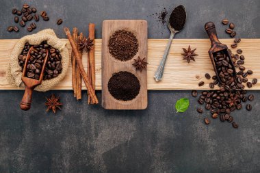 Kahve tozu ve lezzetli malzemelerle kavrulmuş kahve çekirdekleri koyu taşlı arka planda lezzetli kahve yapmak için..