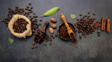 Kahve tozu ve lezzetli malzemelerle kavrulmuş kahve çekirdekleri koyu taşlı arka planda lezzetli kahve yapmak için..