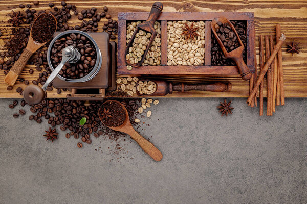 Various of roasted coffee beans in wooden box with manual coffee grinder setup on shabby wooden background.