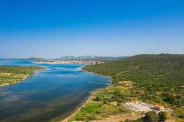 Arka planda Aziz Martin Kilisesi ve Pirovac kasabası bulunan Ivinj arkeoloji sahası, Hırvatistan