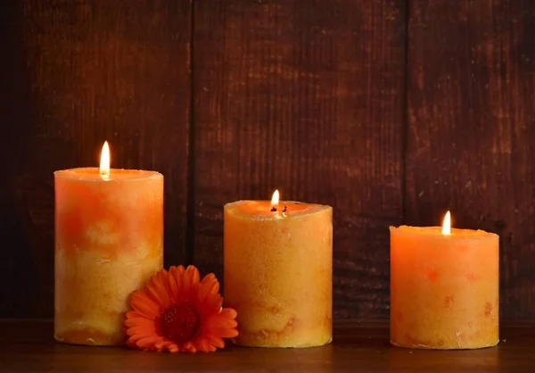 Tre Candele Arancione Cera Fiori Gerbera Sfondo Legno Marrone — Foto Stock