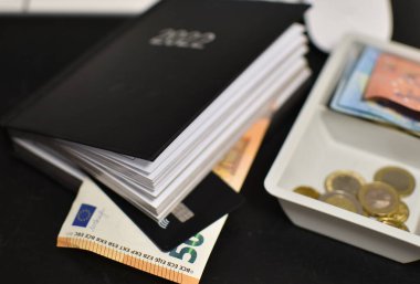 Not defterinin yanındaki kasada kredi kartı, euro faturaları ve madeni paralar.