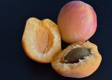 apricots whole and halves with a kernel on a black background