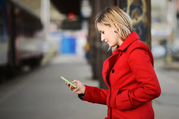 Młoda kobieta czeka na pociąg i SMS-y기차 및 문자 메시지를 기다리는 젊은 여자 — Zdjęcie stockowe