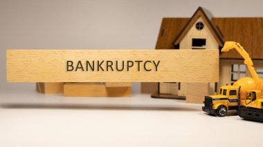 Bankruptcy word written on wooden surface. House and construction concept in background . Mortgage and economy