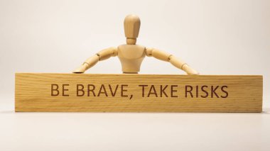 Be brave, take risks written on wooden surface. Motivation and personal development.