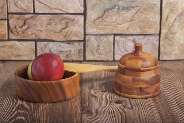 kırmızı elma, kase, ahşaptan yapılmış kaşık ve çömlek kaba bir masa üzerinde tuğla bir duvara karşı duruyor arka plan, kırsal tarz, doğal yiyecek