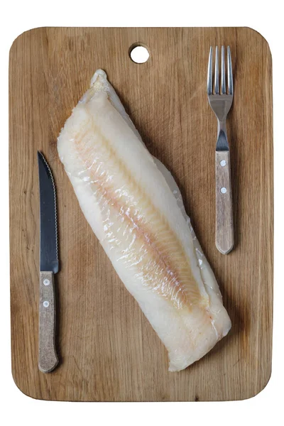frozen cod filet on the oak board with fork and knife
