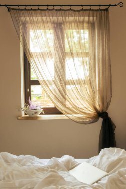 Yatak odasının penceresinden sabah güneşi yatağın üstündeki bilgisayarı aydınlatıyor.