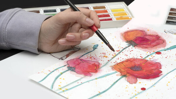 girl's hand with a brush on the background of a drawing of red poppies, watercolor painting lessons concept