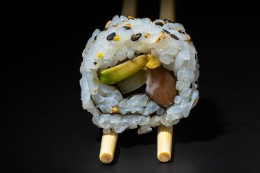 Siyah arka planda uramaki somonu, avokado ve salatalık.