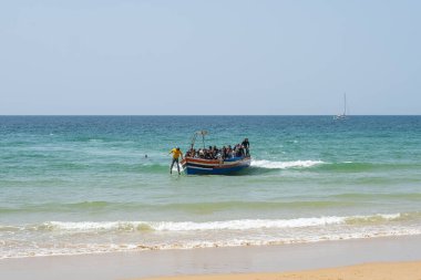 Arrival of a boat to the coast with people jumping